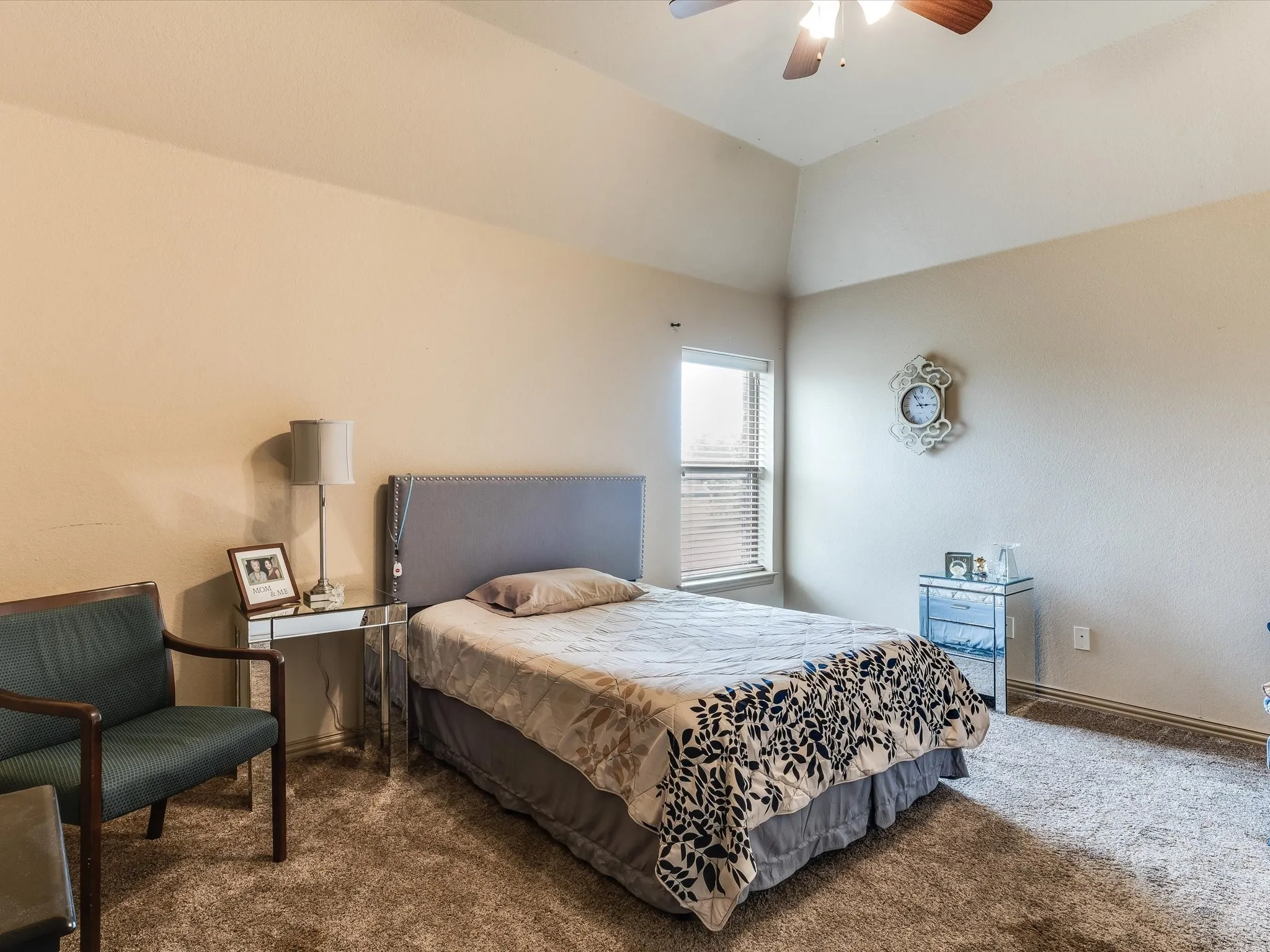 Carpeted room featuring a window with blinds, a vaulted ceiling, and a ceiling fan