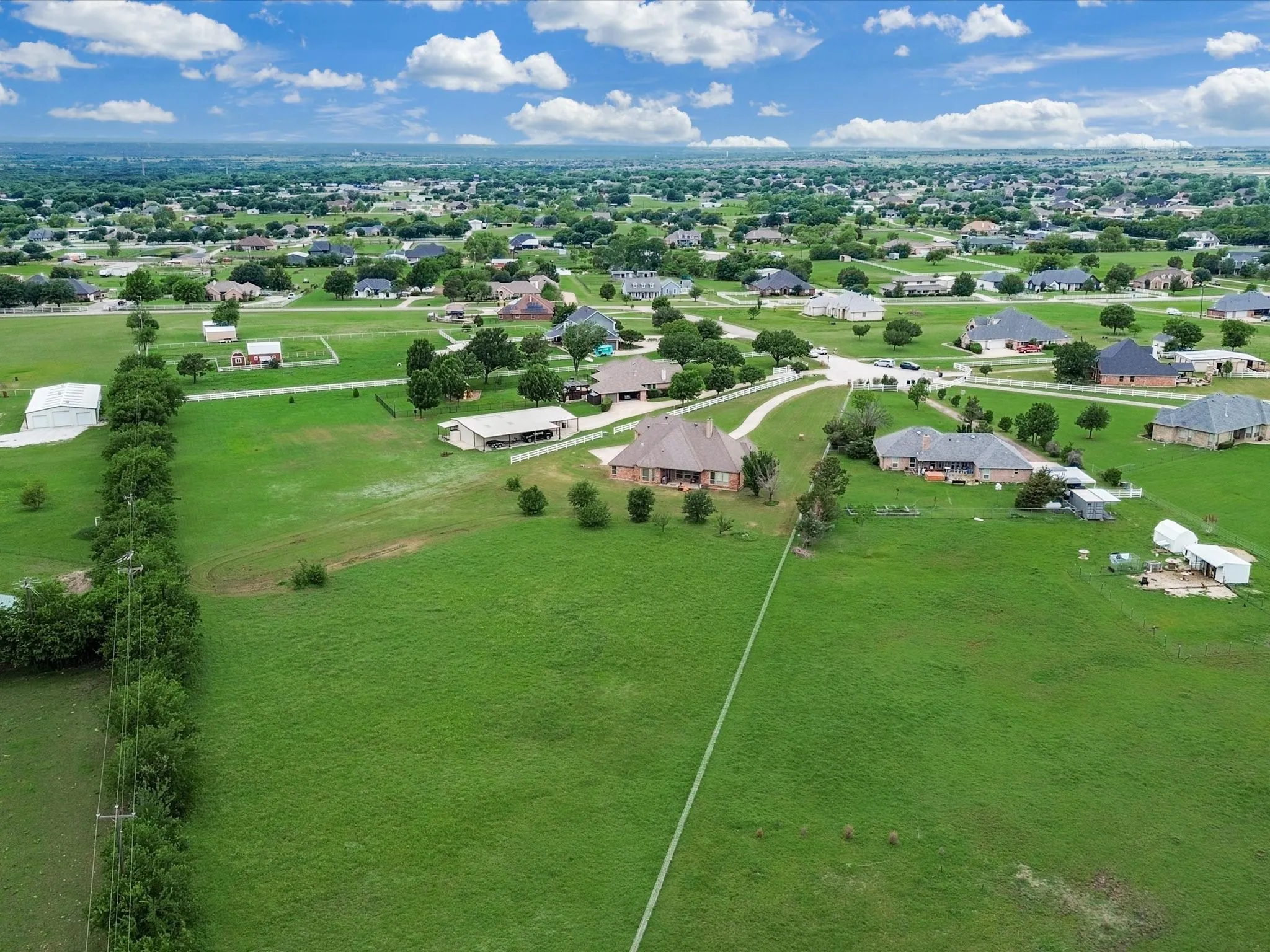 Expansive green acreage featuring a clear boundary line and distant residential homes