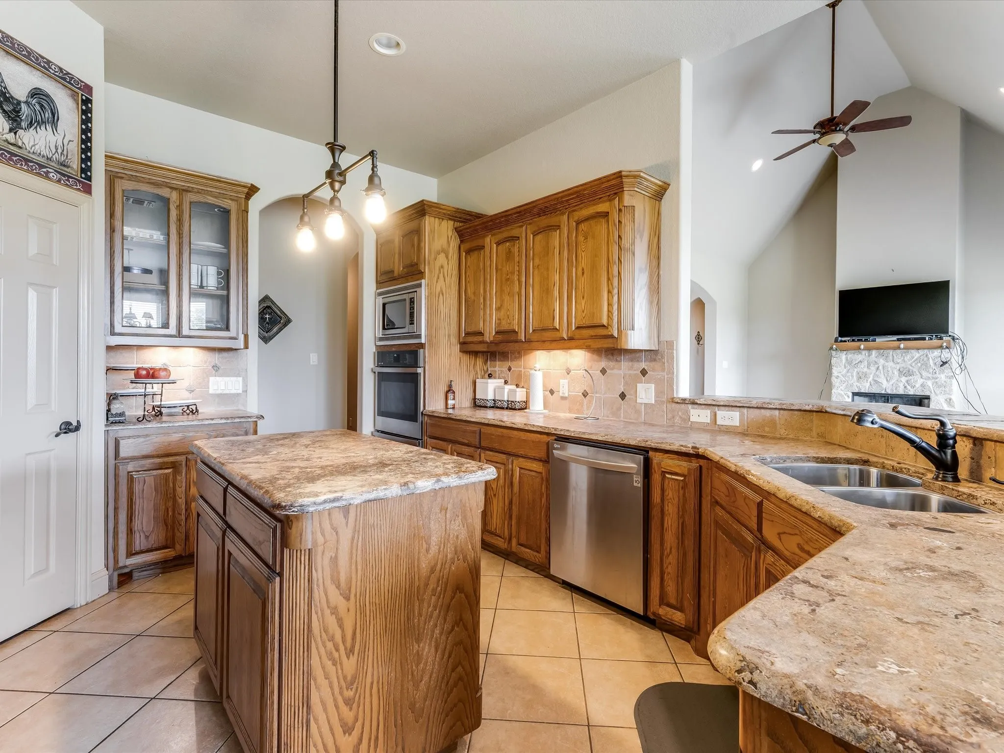 Kitchen featuring a center island, wood cabinetry, stone-finish countertops, stainless steel appliances, and a tile backsplash