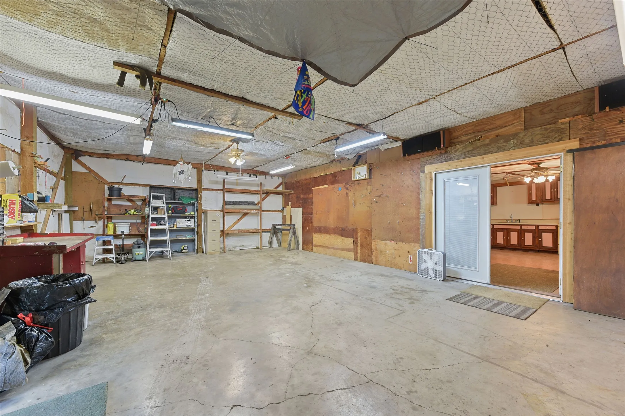 Includes Large Air compressor, Sand Blast cabinet, Built in Table saw, and Radial arm saw. With view of One Bedroom Apartment through French Doors.