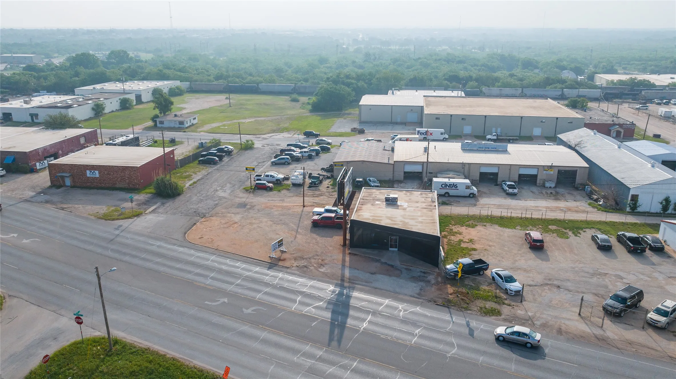 Extensive commercial property featuring multiple structures, paved access from a main thoroughfare, and a large gravel parking area