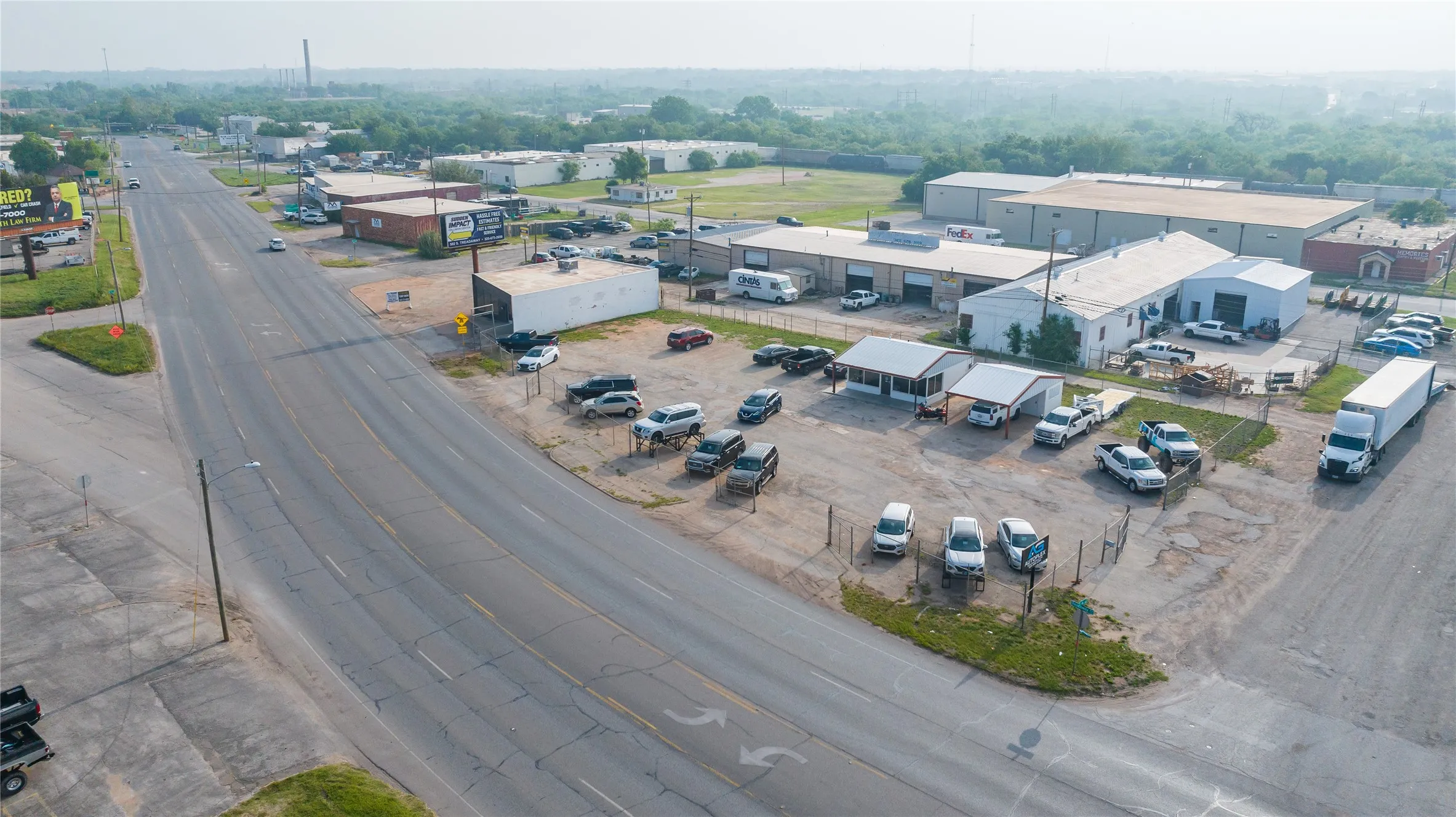 Commercial property featuring multiple buildings, extensive asphalt and gravel parking areas, and a paved road frontage