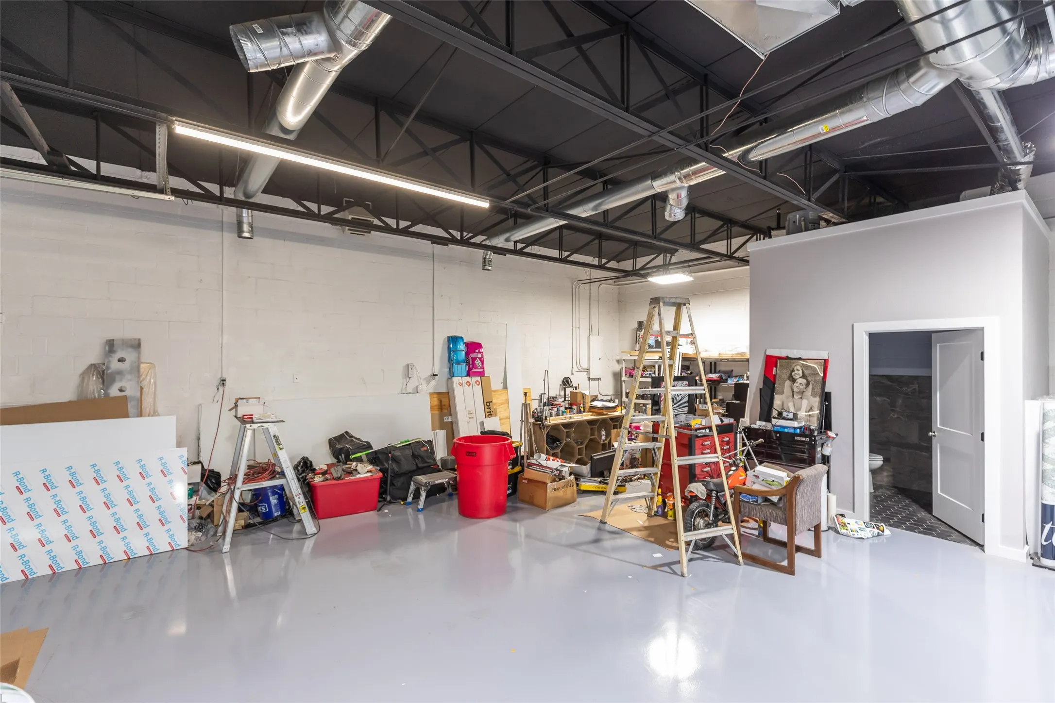Spacious interior featuring a light gray epoxy floor and exposed ceiling with ductwork