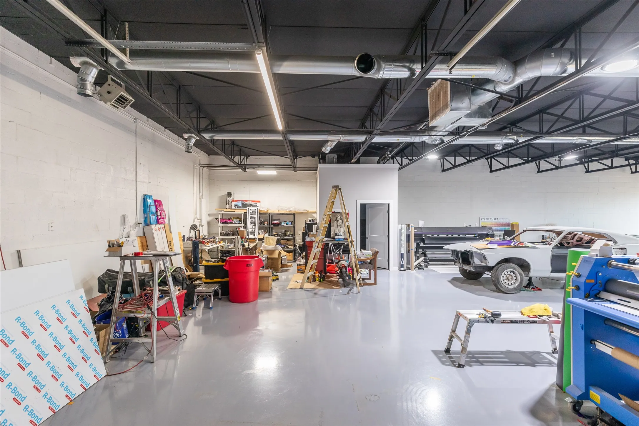 Spacious commercial interior featuring a high, exposed ceiling with black structural beams and ductwork