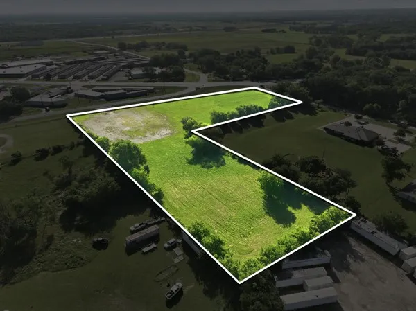 L-shaped parcel featuring lush green ground cover and scattered trees