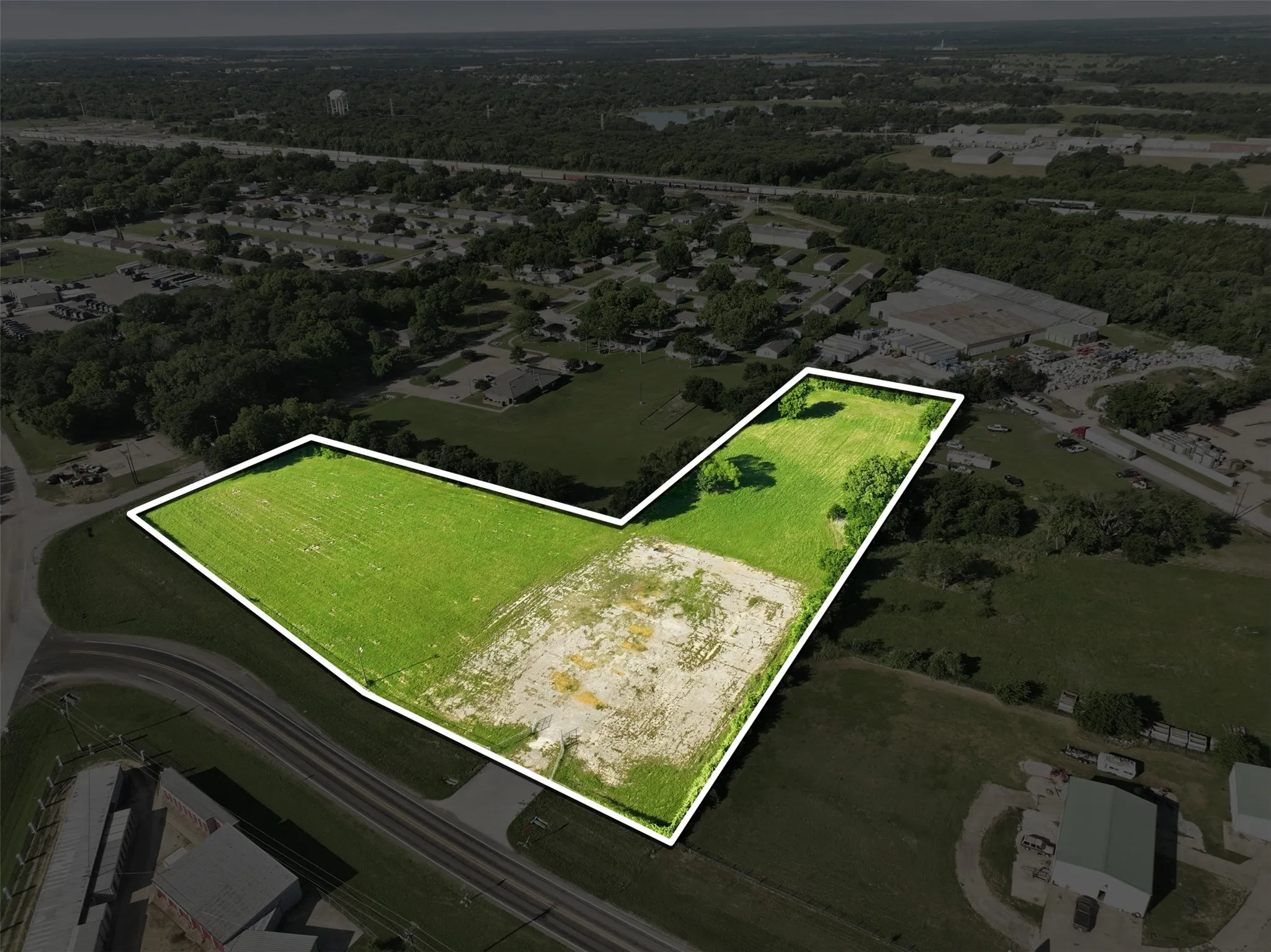 Expansive L-shaped lot outlined in white, featuring significant green space and a partial cleared area