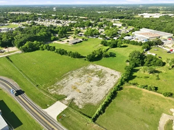 Expansive undeveloped land featuring a cleared building pad and a frontage road access point