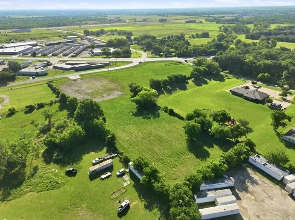Expansive green landscape featuring varied terrain, surrounding commercial structures, and distant infrastructure