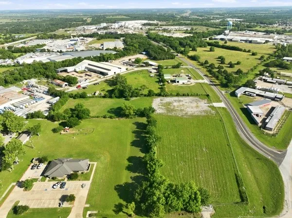 Aerial overview displaying multiple parcels of green space, commercial structures, and paved roads