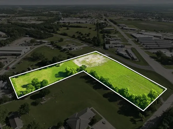 Expansive L-shaped property featuring verdant green fields and mature trees