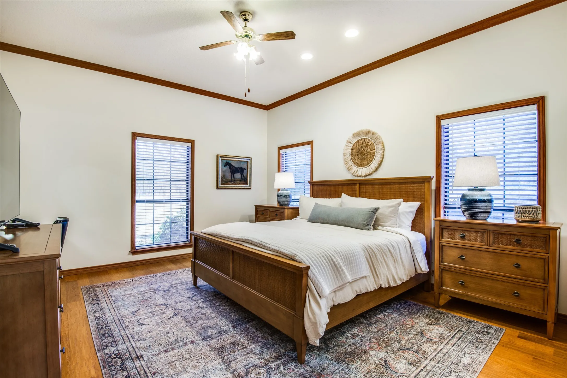 Spacious room featuring wood-finish flooring, white walls, and a ceiling fan