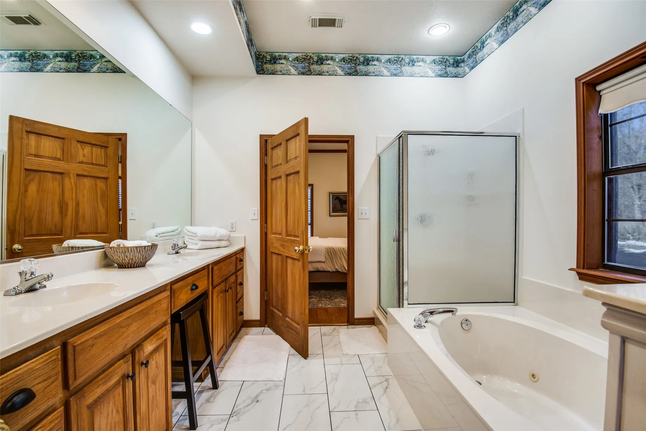 Bathroom featuring a double vanity with light wood cabinetry, white stone countertops, and dual sinks