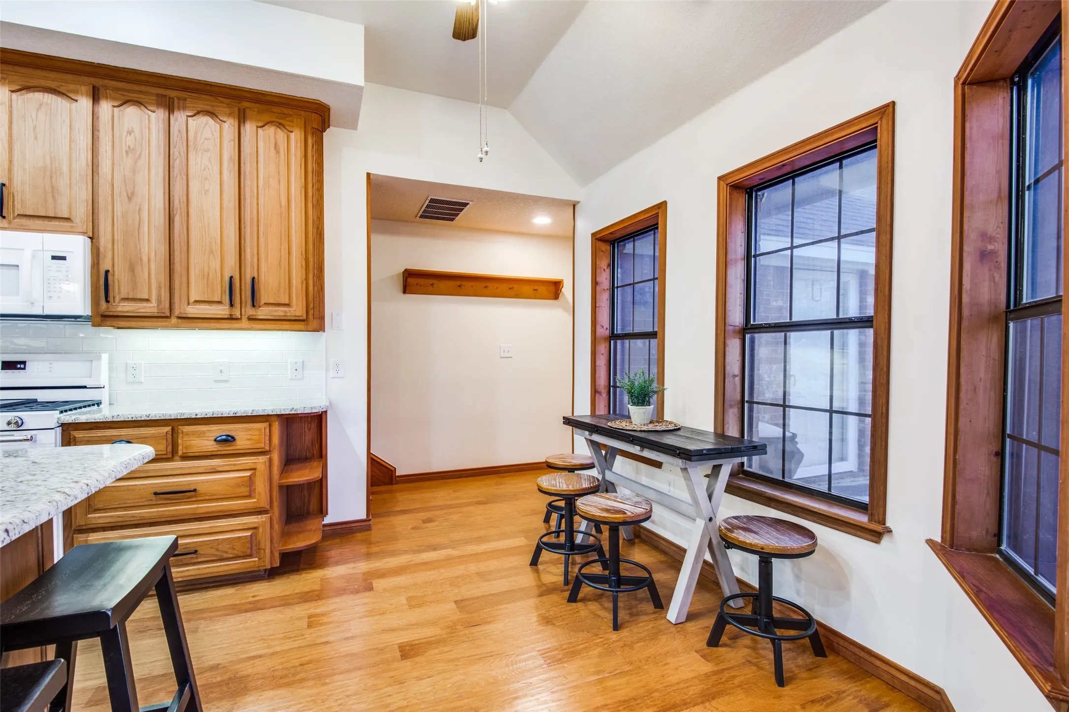 Kitchen area featuring light wood cabinetry, white subway tile backsplash, and granite countertops