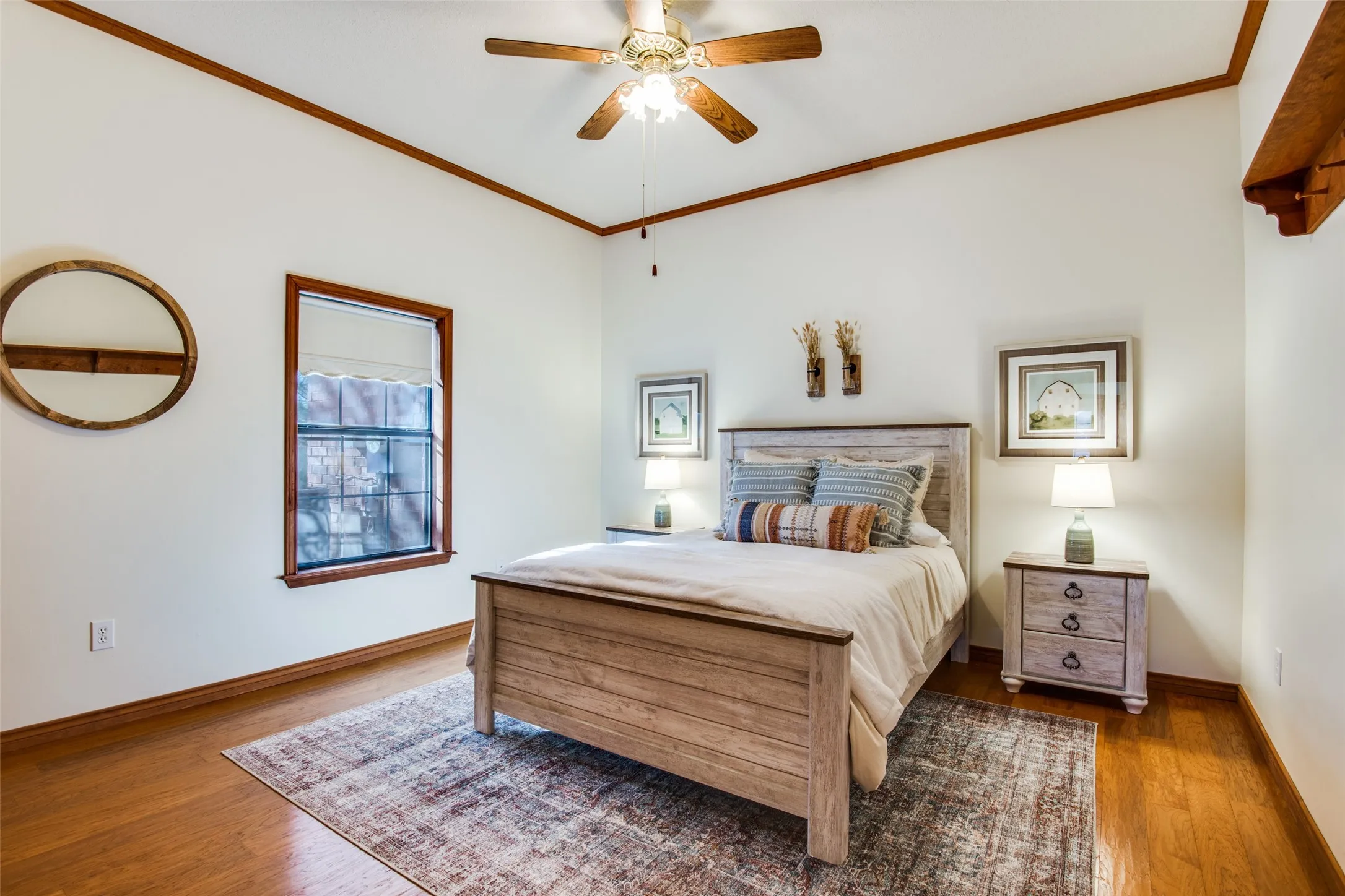 Vaulted ceiling with a ceiling fan, wood-finish flooring, and a single window with wood trim