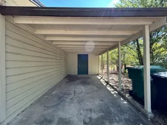 Covered carport featuring a concrete floor, horizontal siding, and a dark-toned door