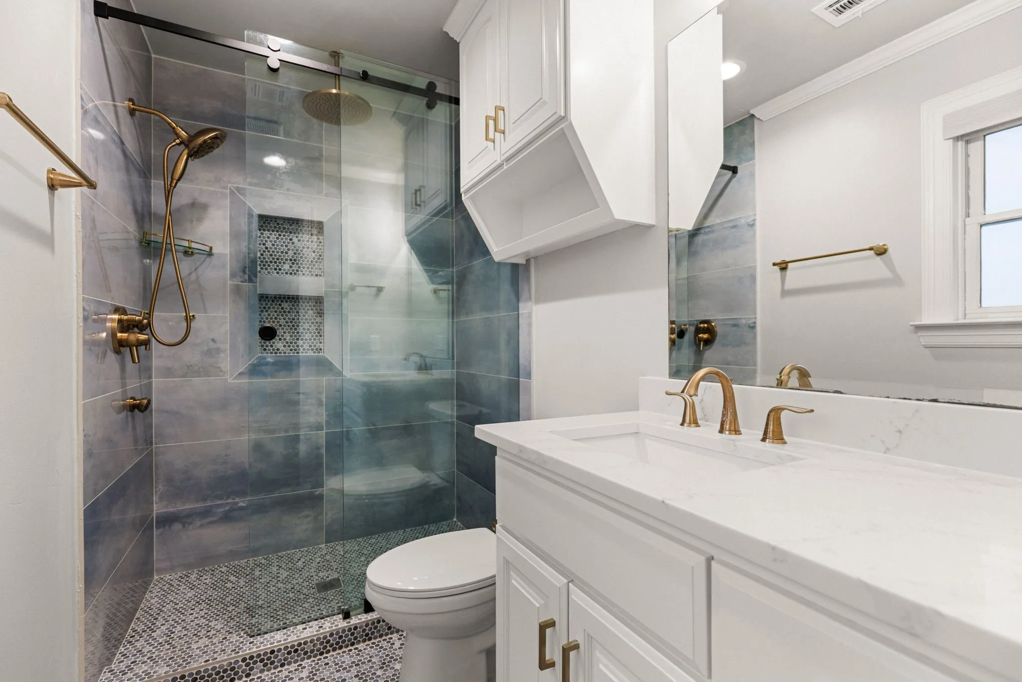 Bathroom featuring a glass-enclosed shower with subway tile and mosaic flooring, complete with a rain shower head and handheld sprayer