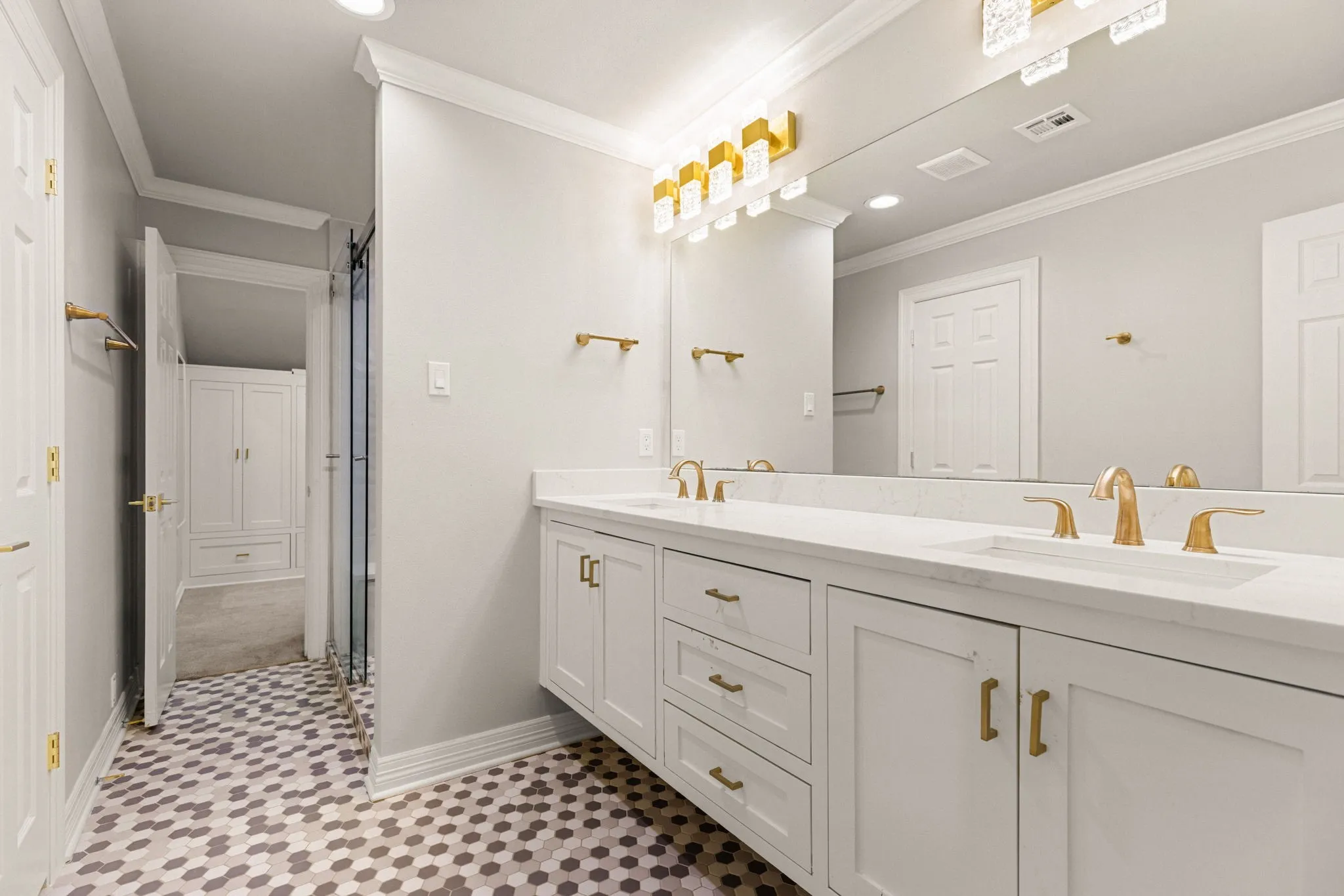 Bathroom vanity featuring a dual-sink design with brass fixtures and white countertops