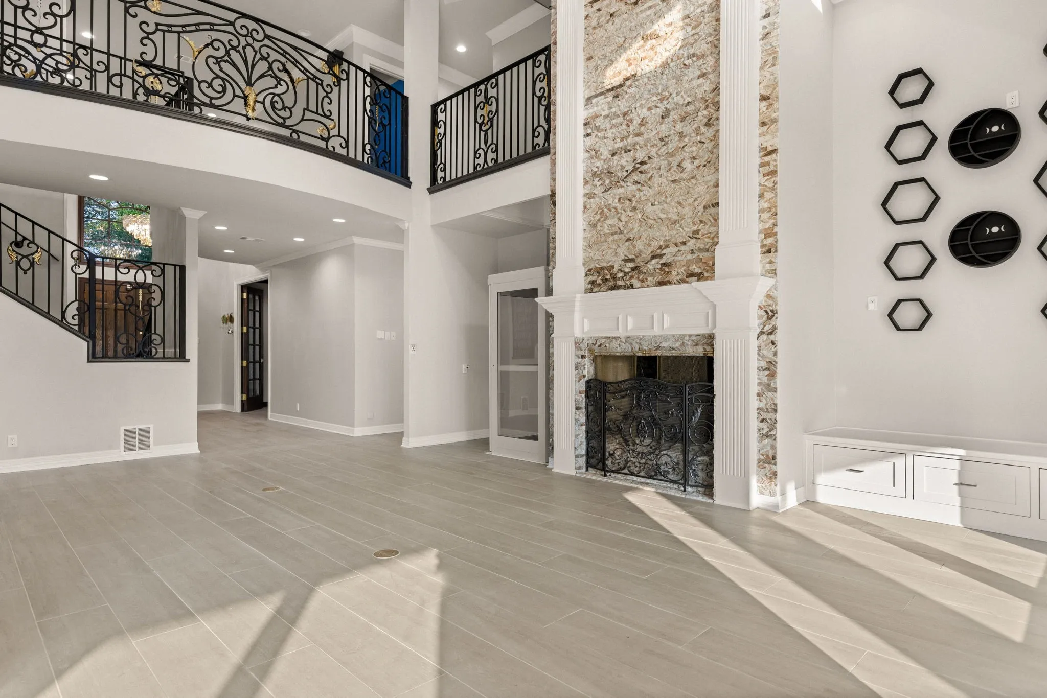 Two-story living area featuring a stone accent wall, decorative fireplace with ornate screen, and built-in cabinetry