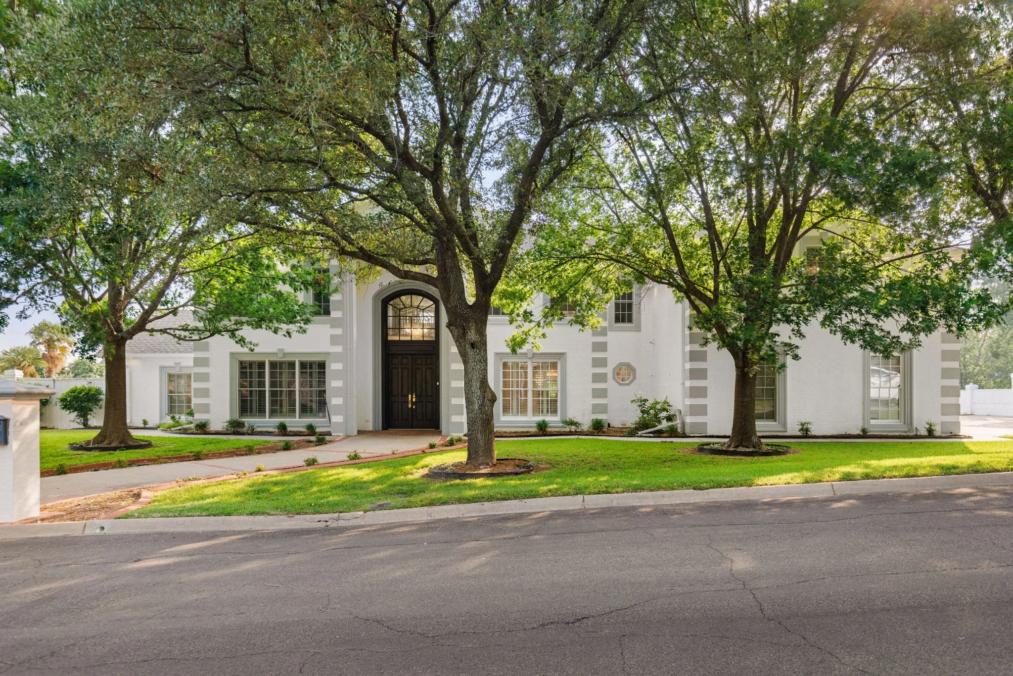 Ftopaved walkway, mature trees, and landscaping elements
