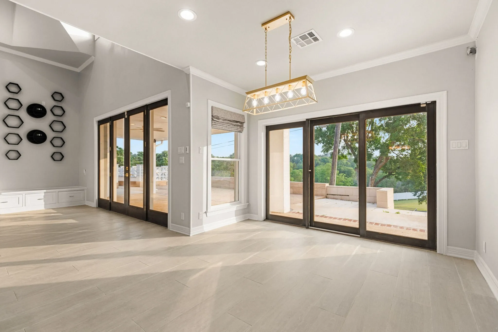 Spacious interior featuring light wood-finish flooring and a contemporary linear chandelier