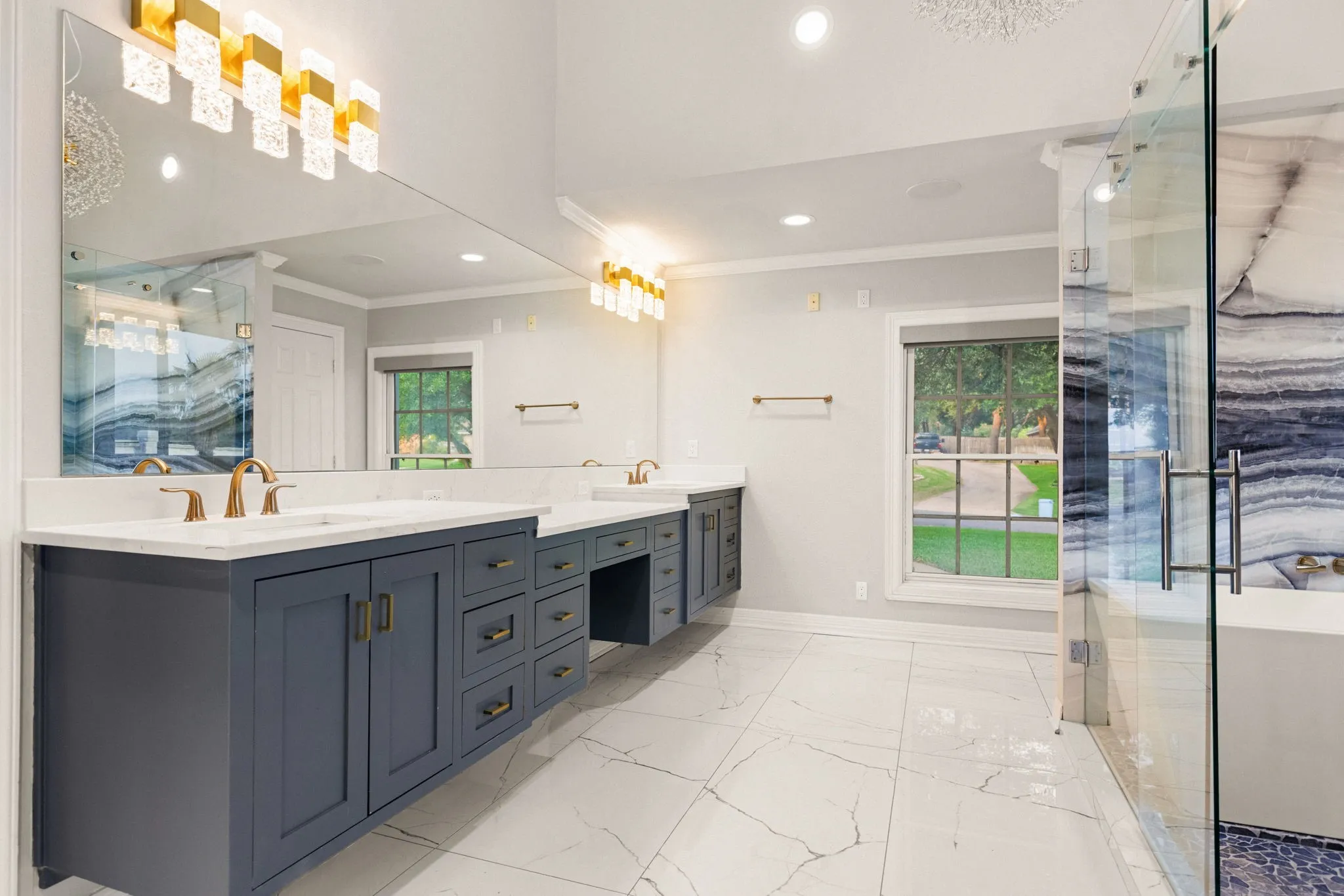 Spacious bathroom featuring an extended dual vanity with dark cabinetry and brass hardware, complemented by white countertops