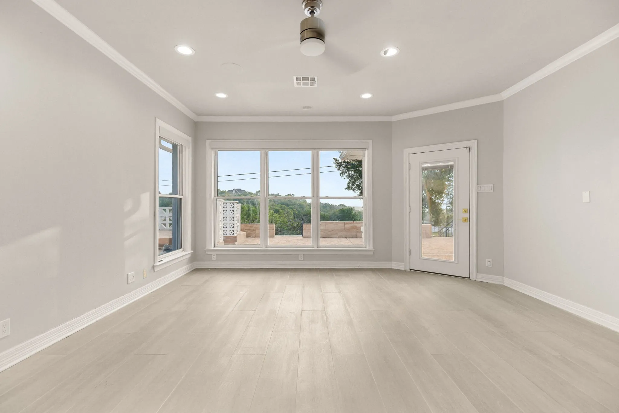 Expansive room with light wood-finish flooring and a bright neutral paint palette