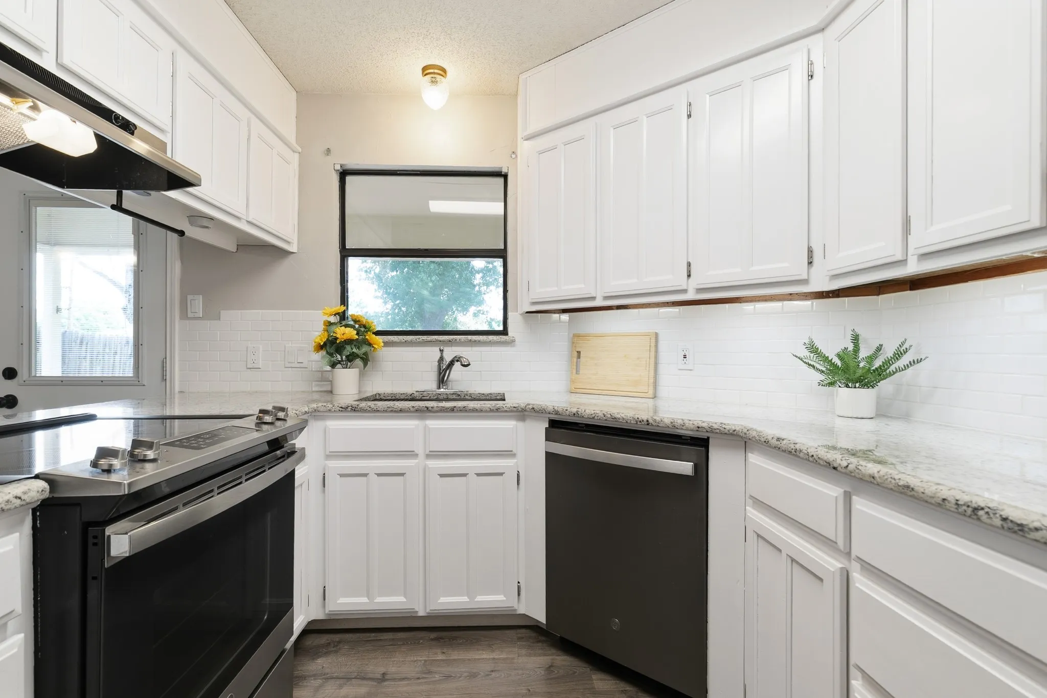 Kitchen featuring white cabinetry, light-toned countertops, a white subway tile backsplash, stainless steel appliances, and wood-finish flooring