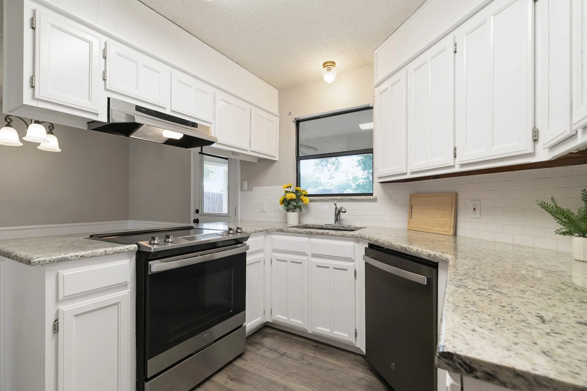 Kitchen featuring white cabinetry, light-toned countertops, a stainless steel range, and a black dishwasher