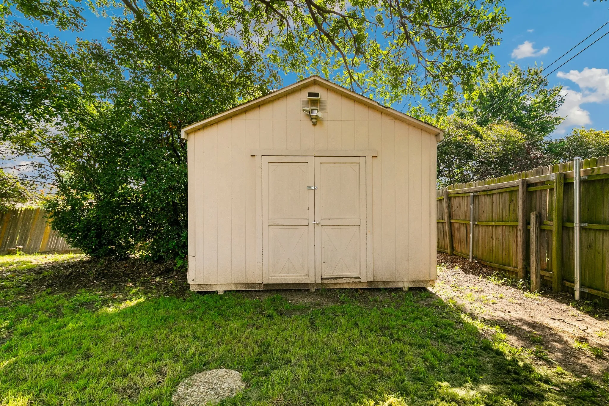Gable-roof storage shed with double doors, set on a wood base