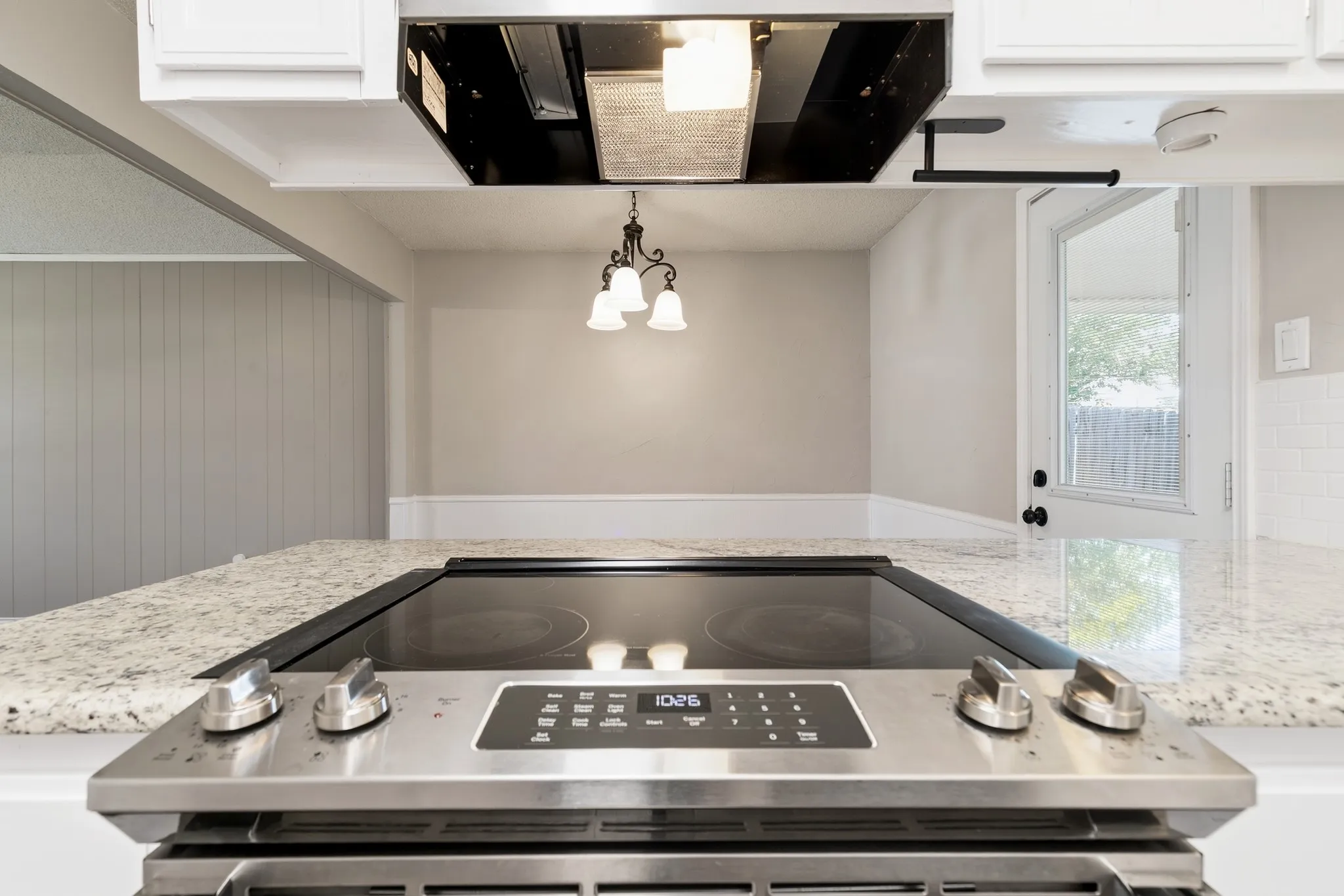 Built-in stainless steel electric range with a black ceramic cooktop, set within a light-toned countertop