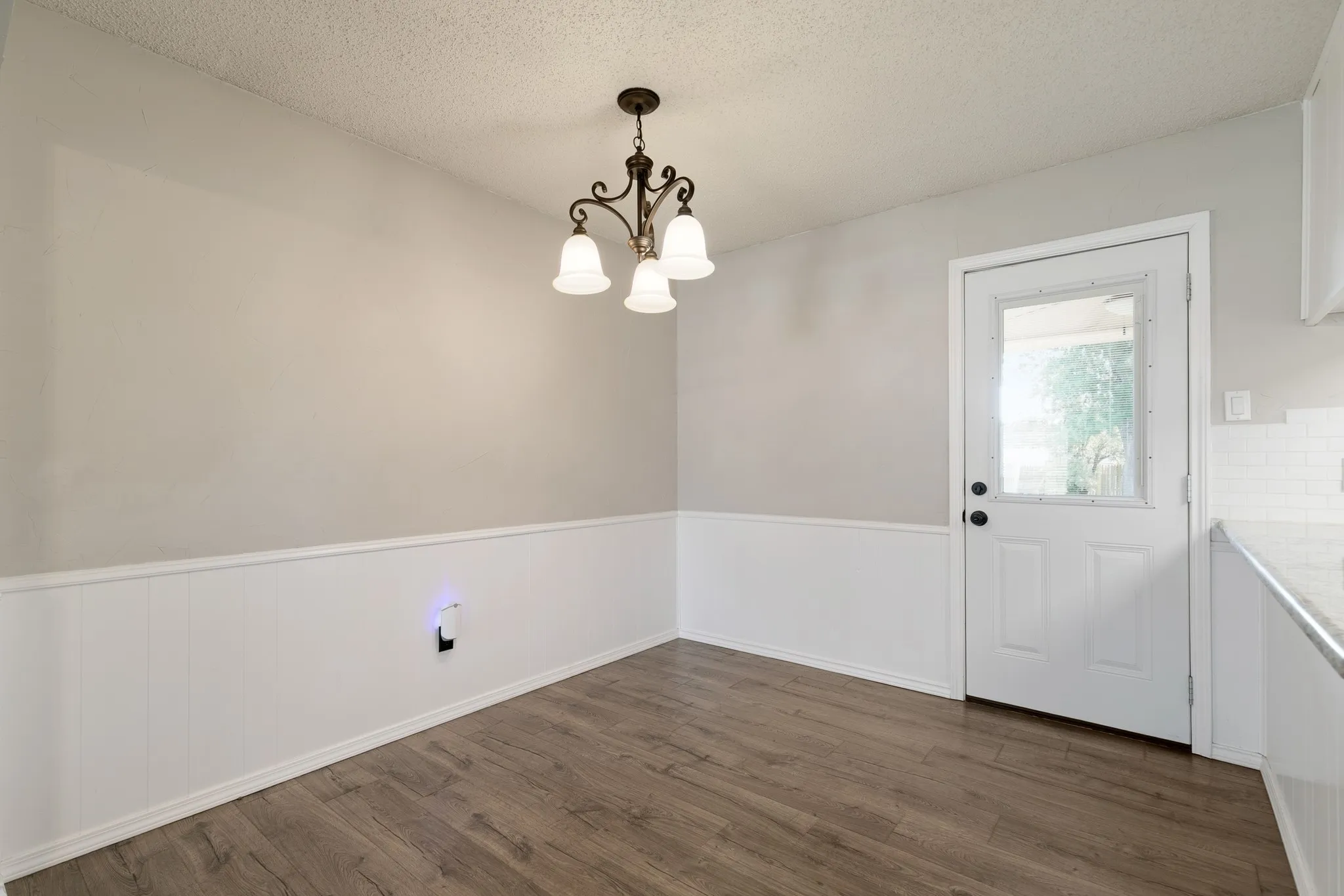 Dining area featuring wood-finish flooring, wainscoting, and a decorative chandelier
