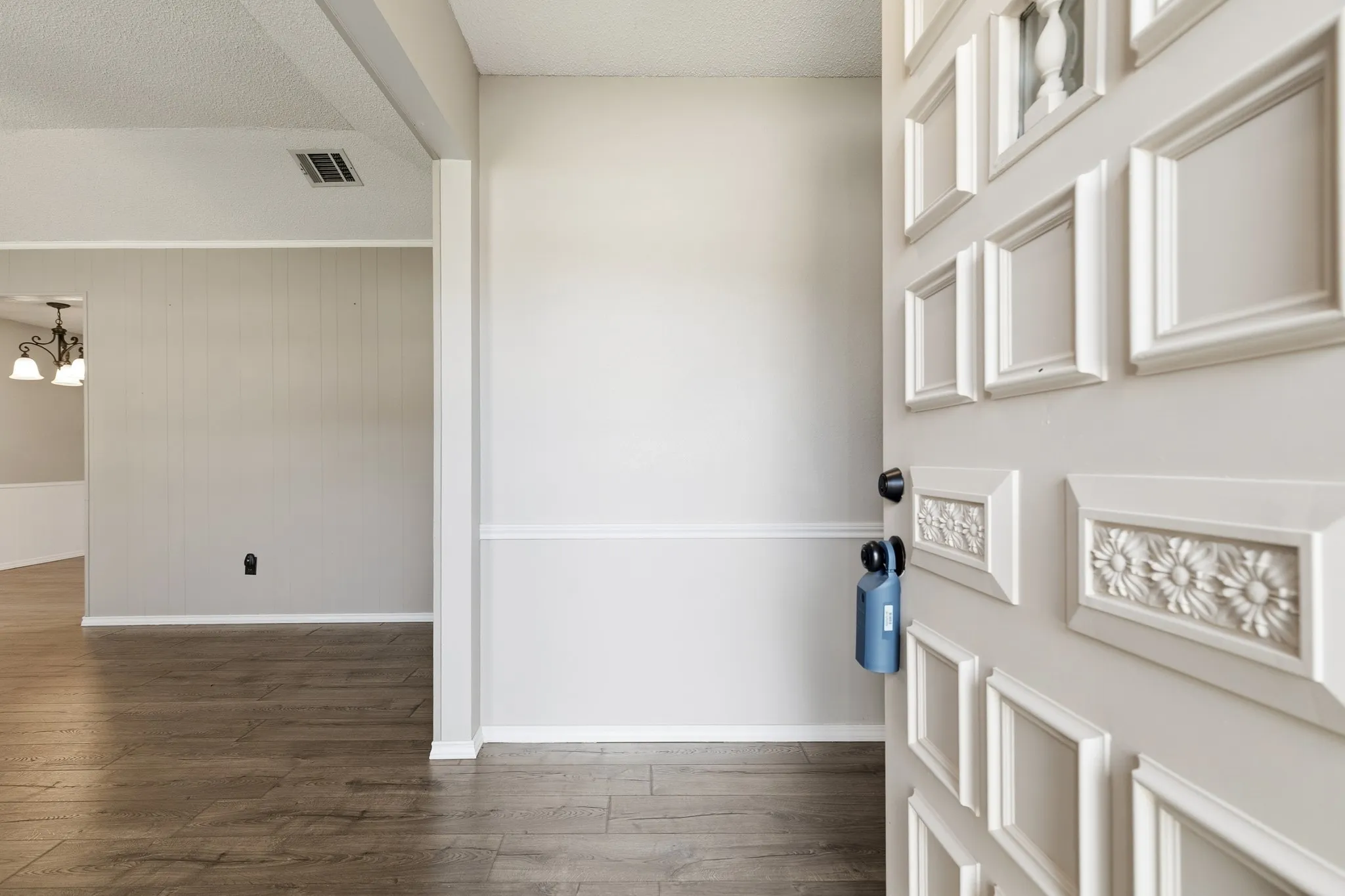 Entryway with decorative paneled door and wood-finish flooring