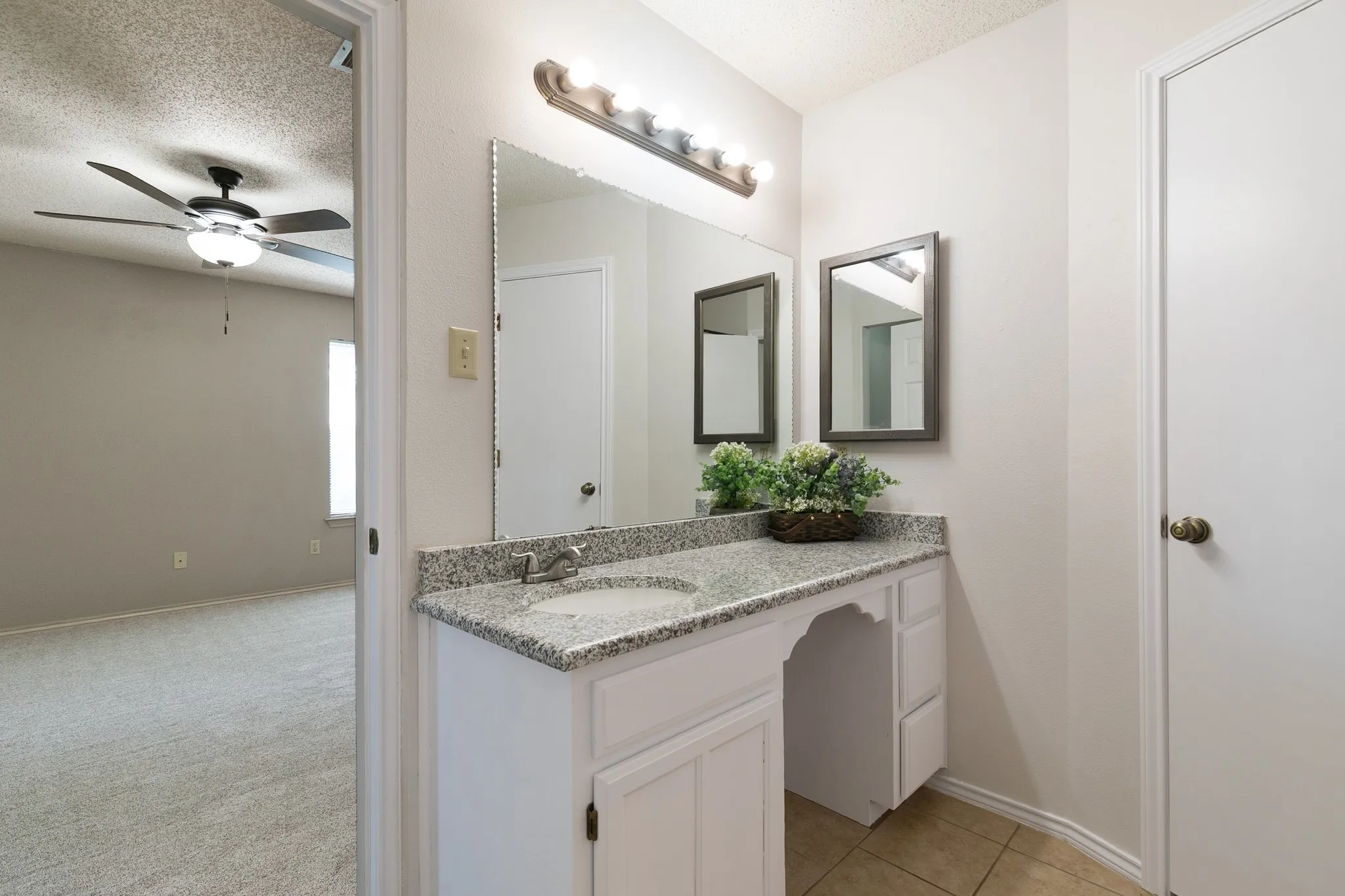 Bathroom vanity featuring a single basin, stone-finish countertop, and white cabinetry with a dedicated knee space