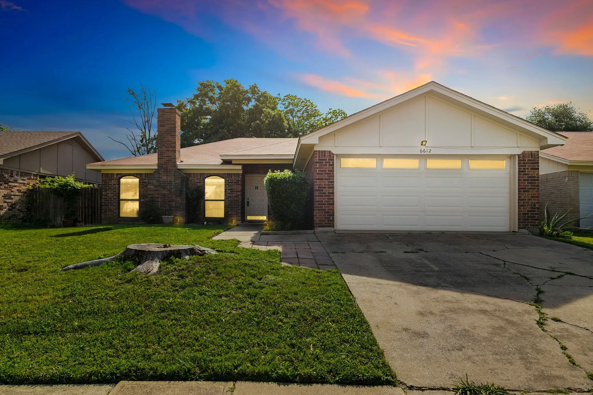 Brick exterior residence featuring an attached garage with a panel door and transom-style windows