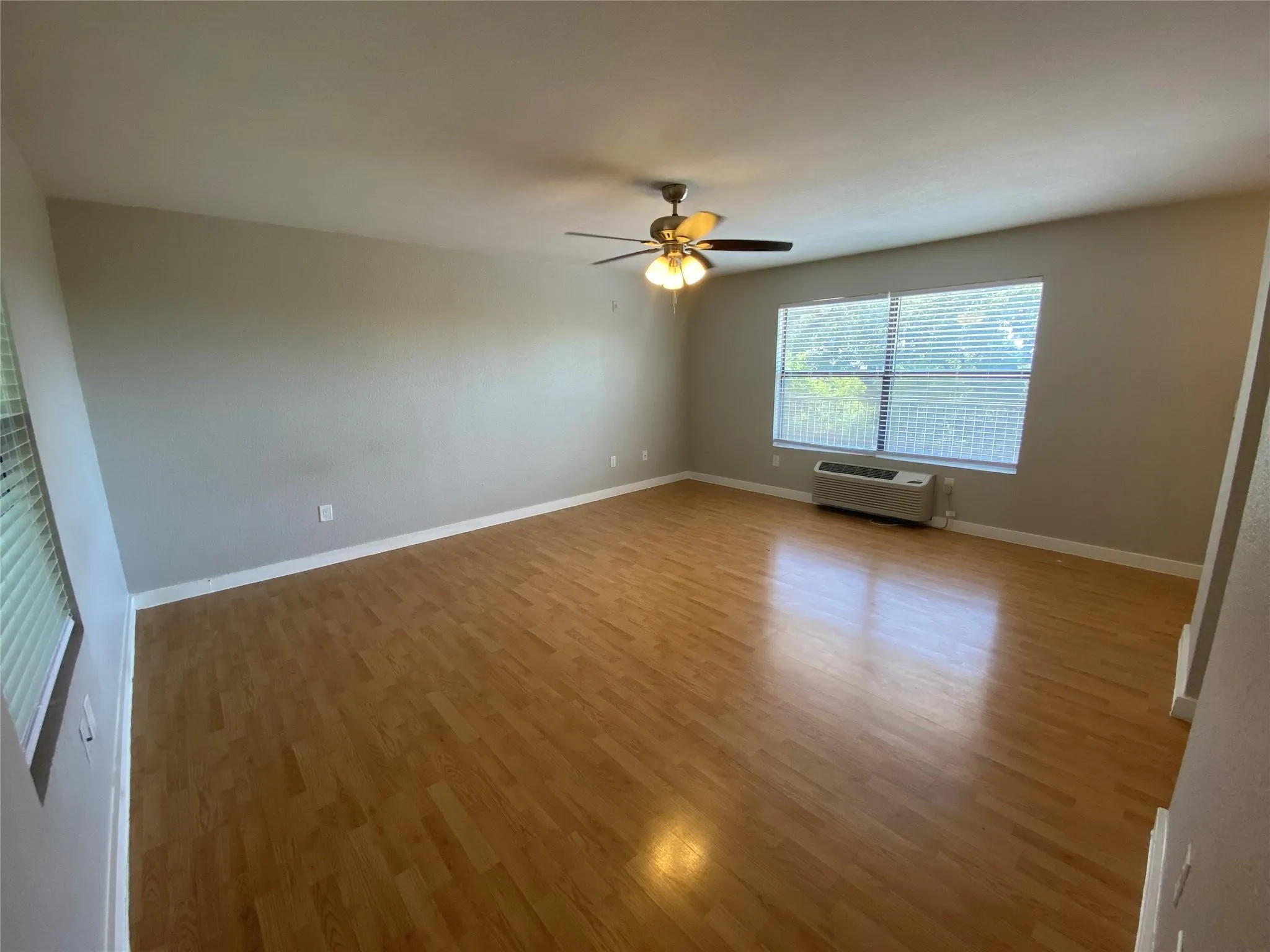Enjoy the expansive living area, beautifully finished with modern wood-toned flooring and large windows that fill the space with natural light.
