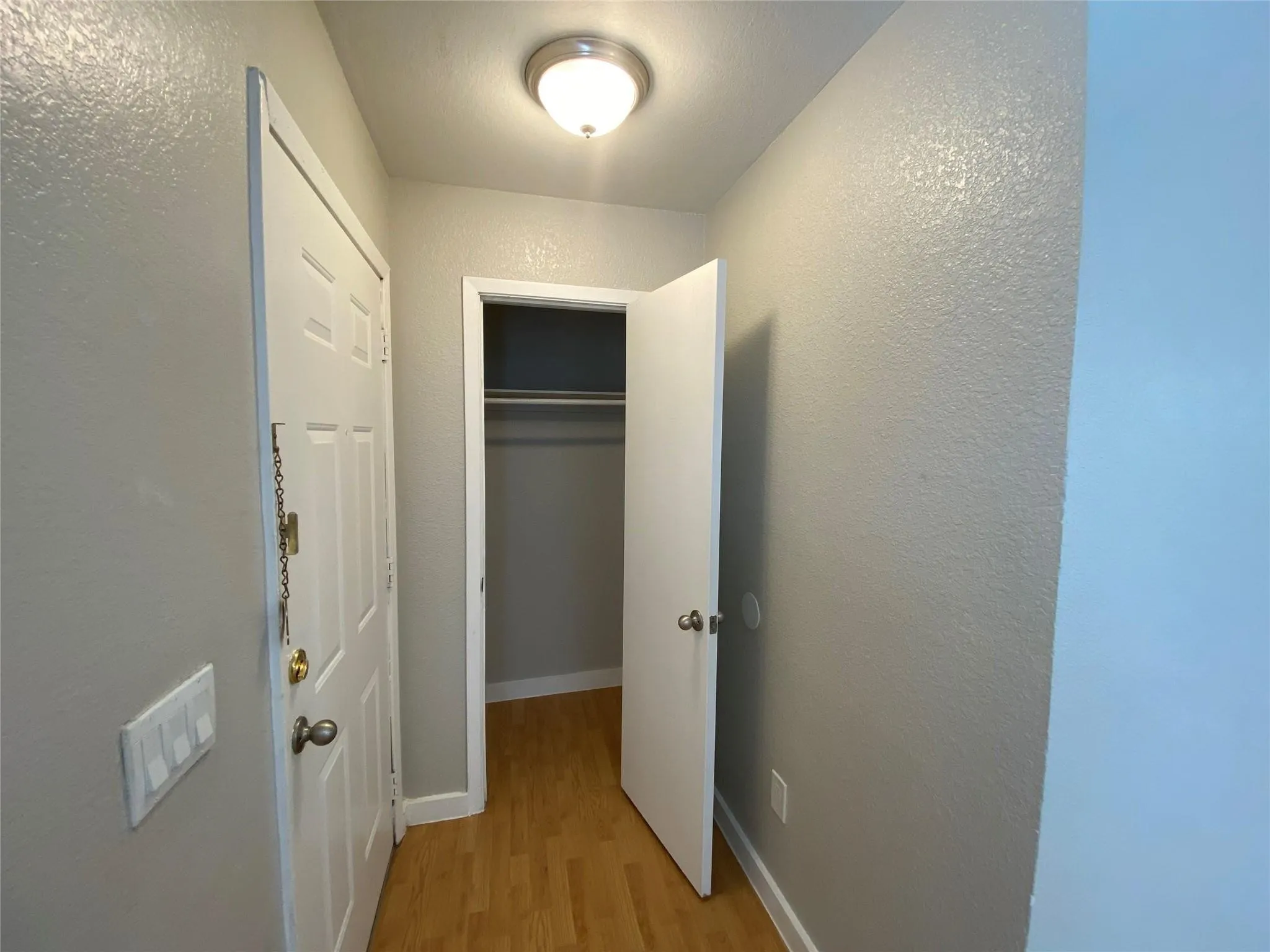 Walk into a welcoming hallway featuring attractive wood-toned flooring and a convenient coat closet, offering a practical and stylish entry.