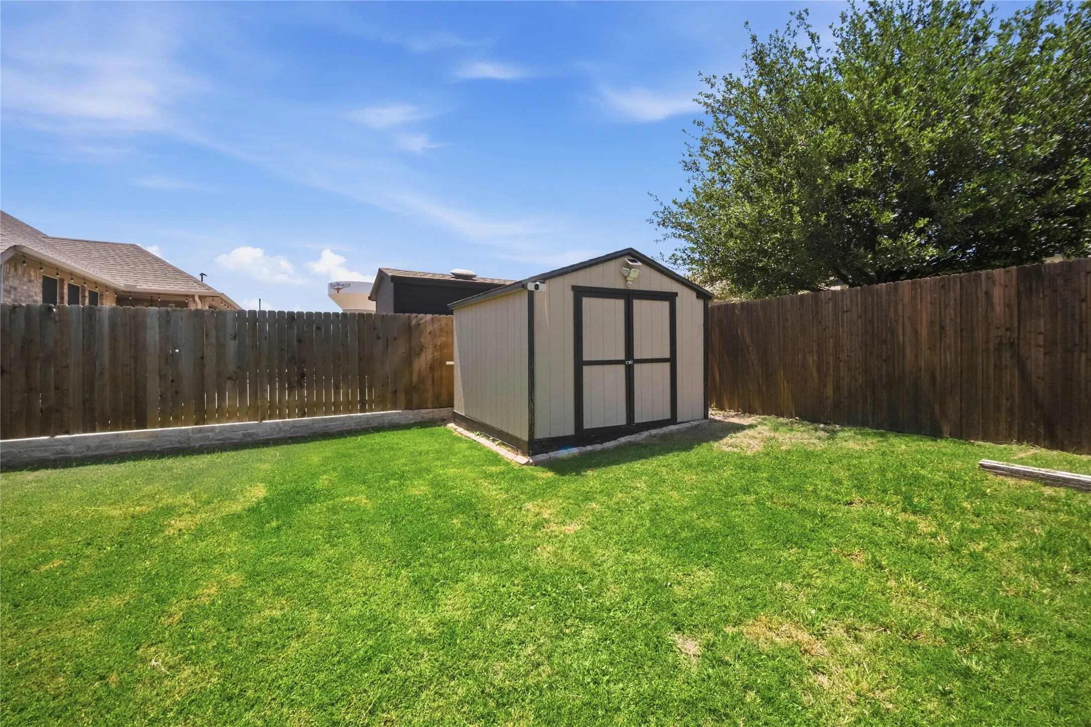 Expansive green lawn with a privacy fence and a storage shed