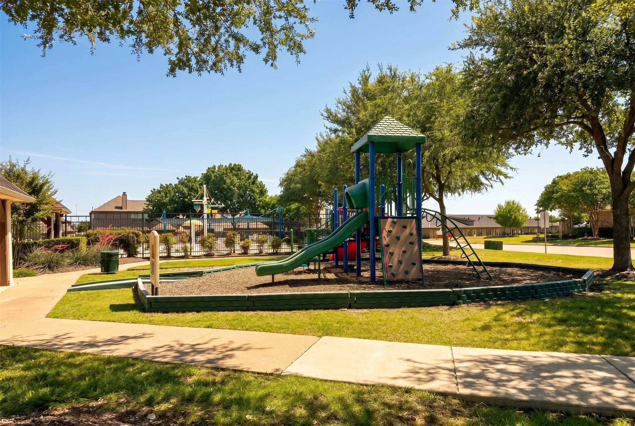 Community playground featuring a multi-level play structure with slide, rock climbing wall, and ladder