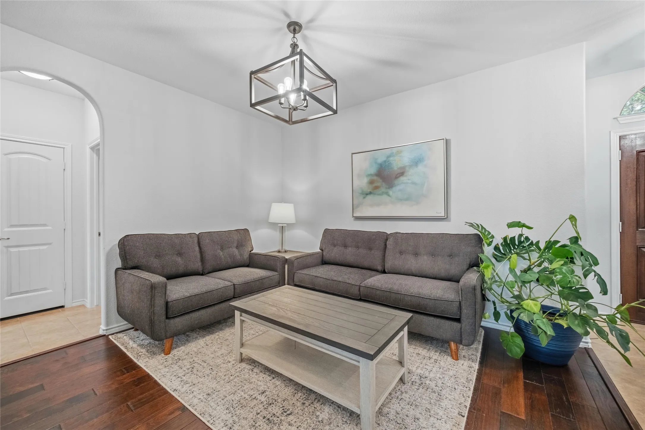 Living area featuring rich wood-finish flooring, an arched doorway, and a contemporary ceiling fixture