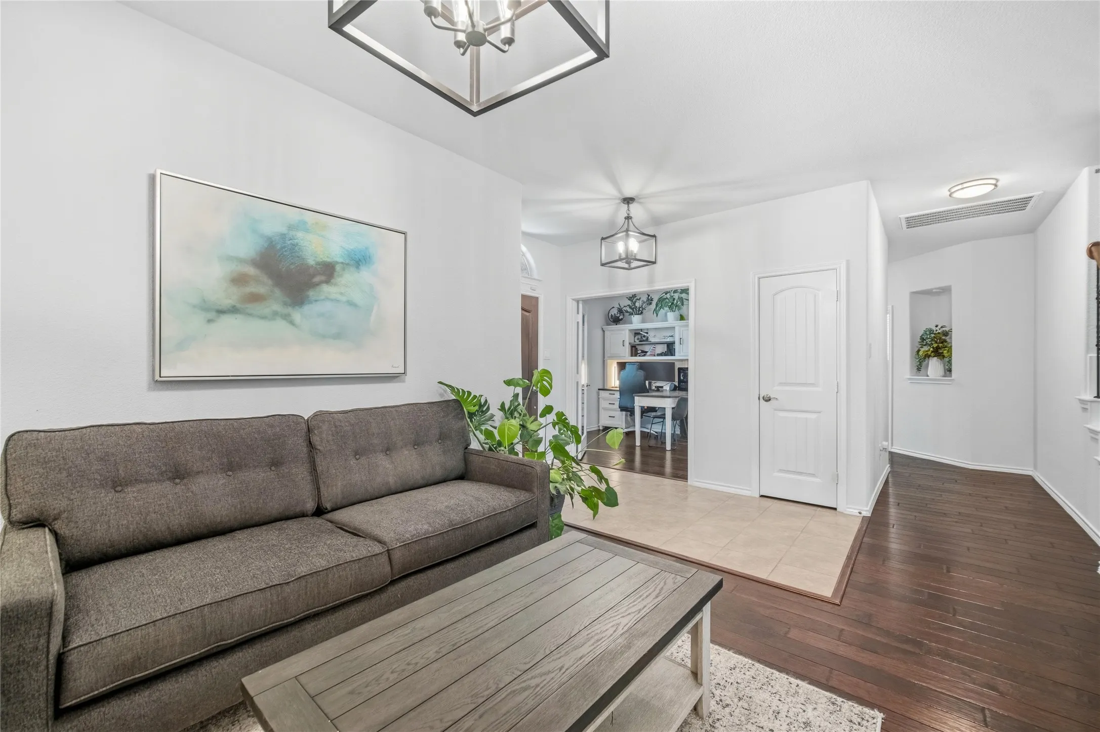 Spacious living area featuring dark wood-finish flooring and a contemporary overhead light fixture