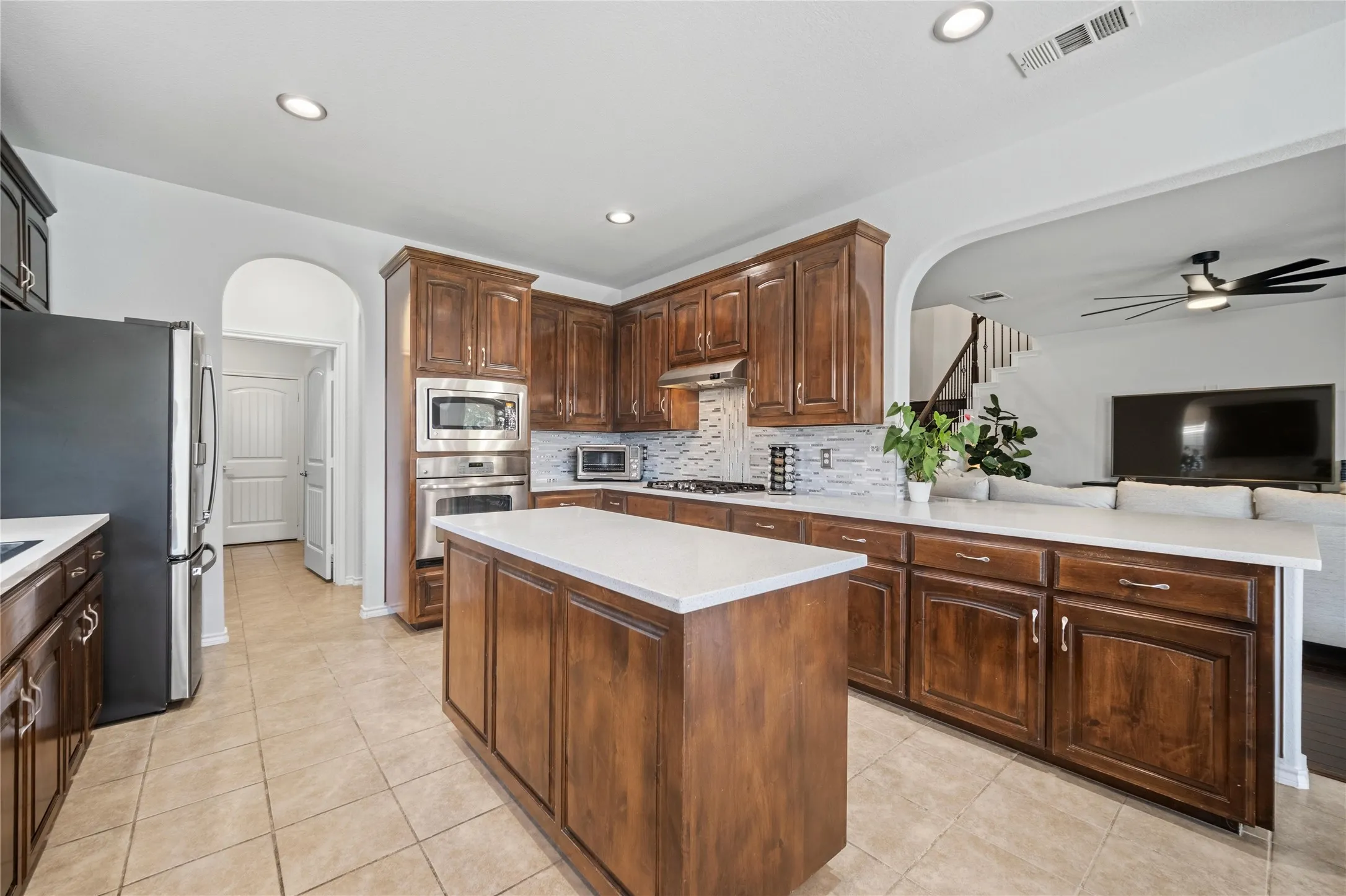 Kitchen featuring a central island with countertop, rich wood-finish cabinetry, stainless steel appliances, tile flooring, and recessed lighting