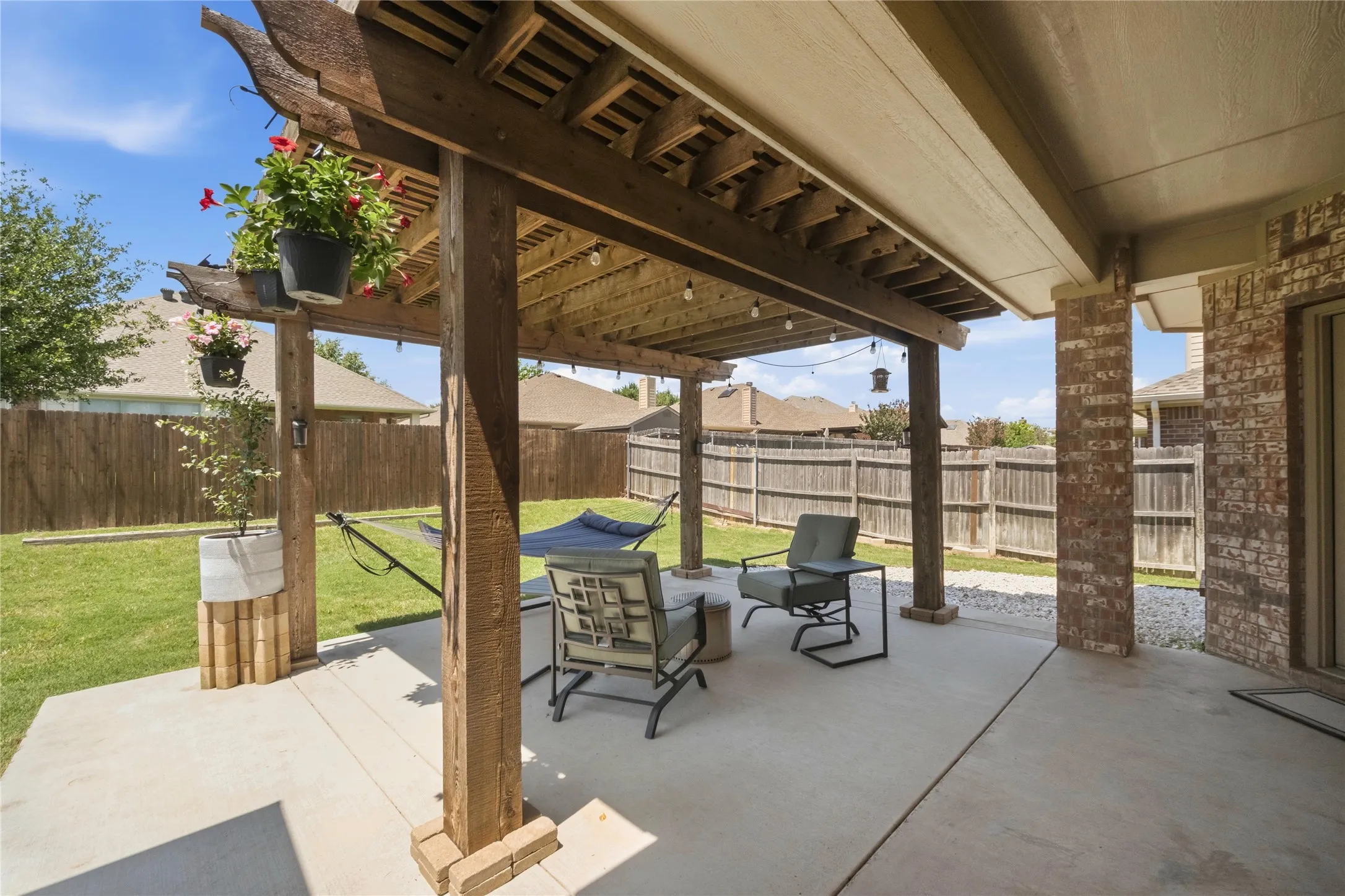 Expansive concrete patio featuring a wood pergola and string lighting