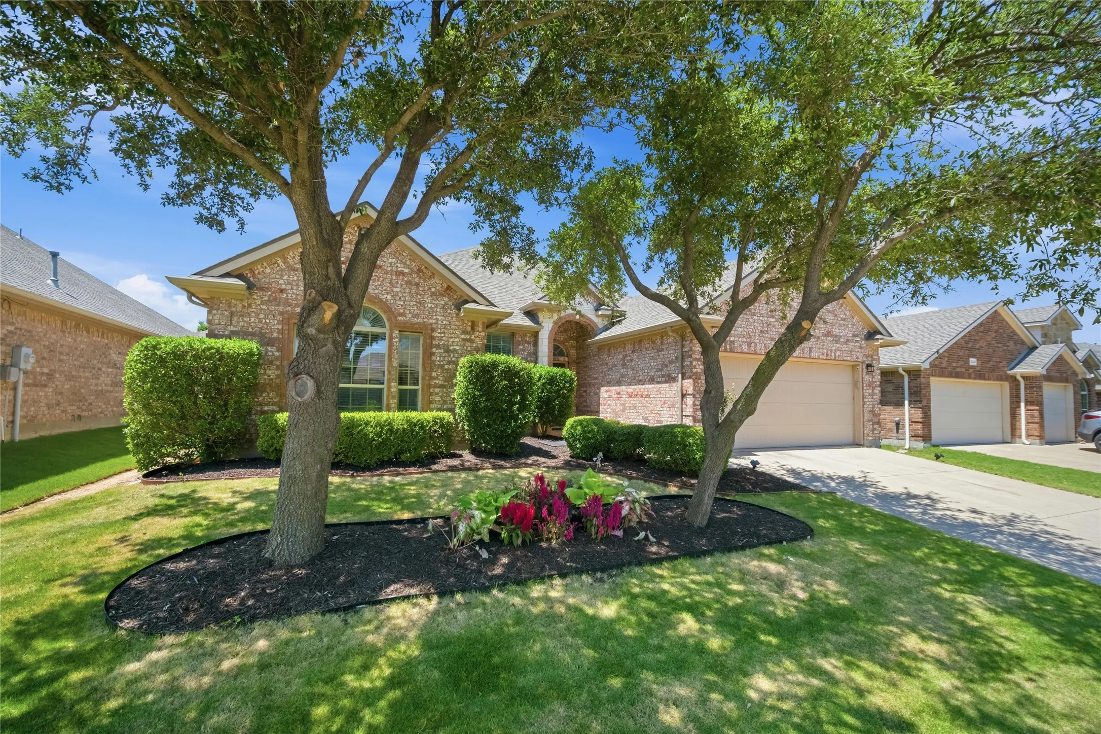Brick exterior with arched window details, a two-car garage, and a concrete driveway