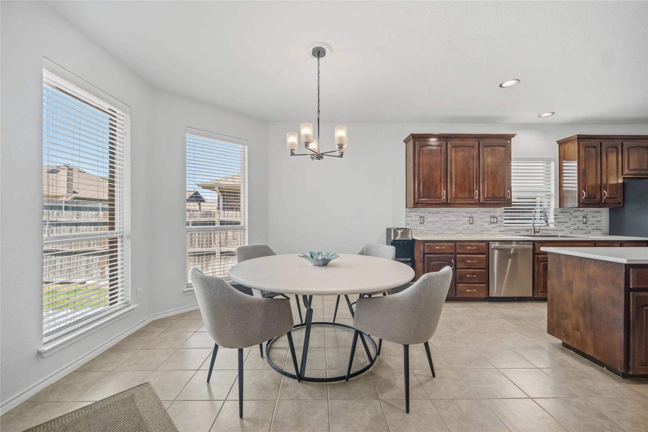 Kitchen and dining area featuring tile flooring, dark wood-finish cabinetry, stainless steel appliances, and a tiled backsplash