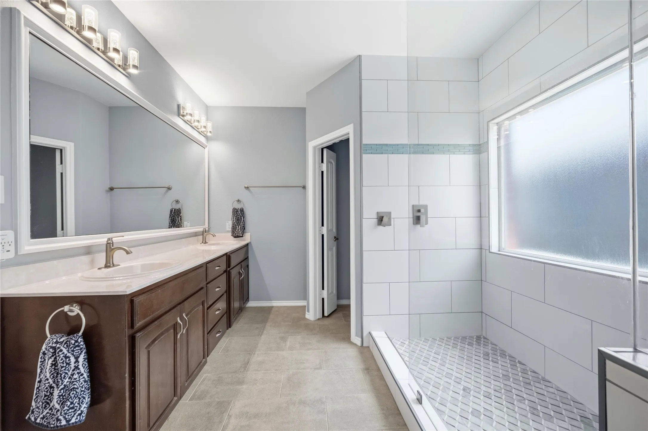 Dual vanity featuring warm wood-finish cabinetry and light-toned countertops