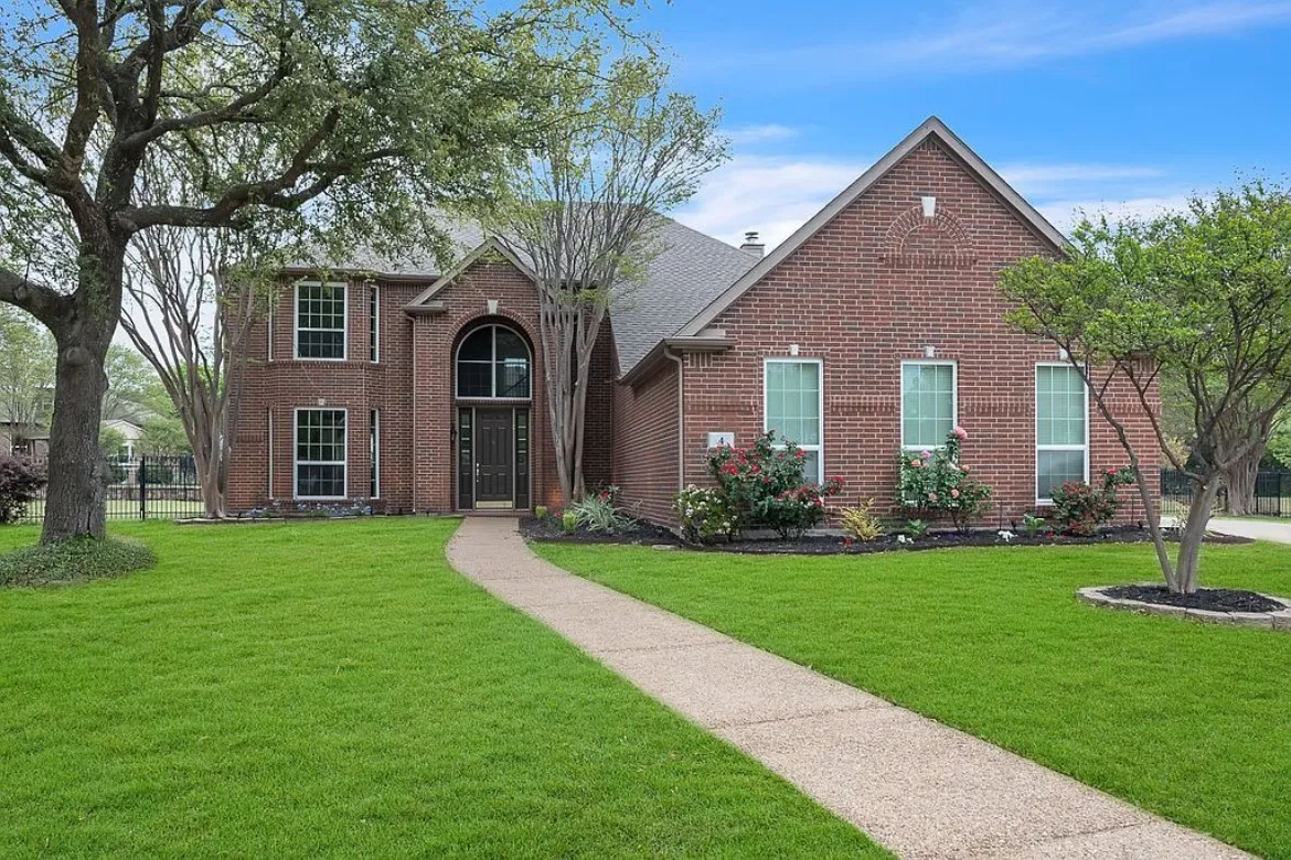 Brick exterior residence featuring a gabled roofline and an arched window above the front entry