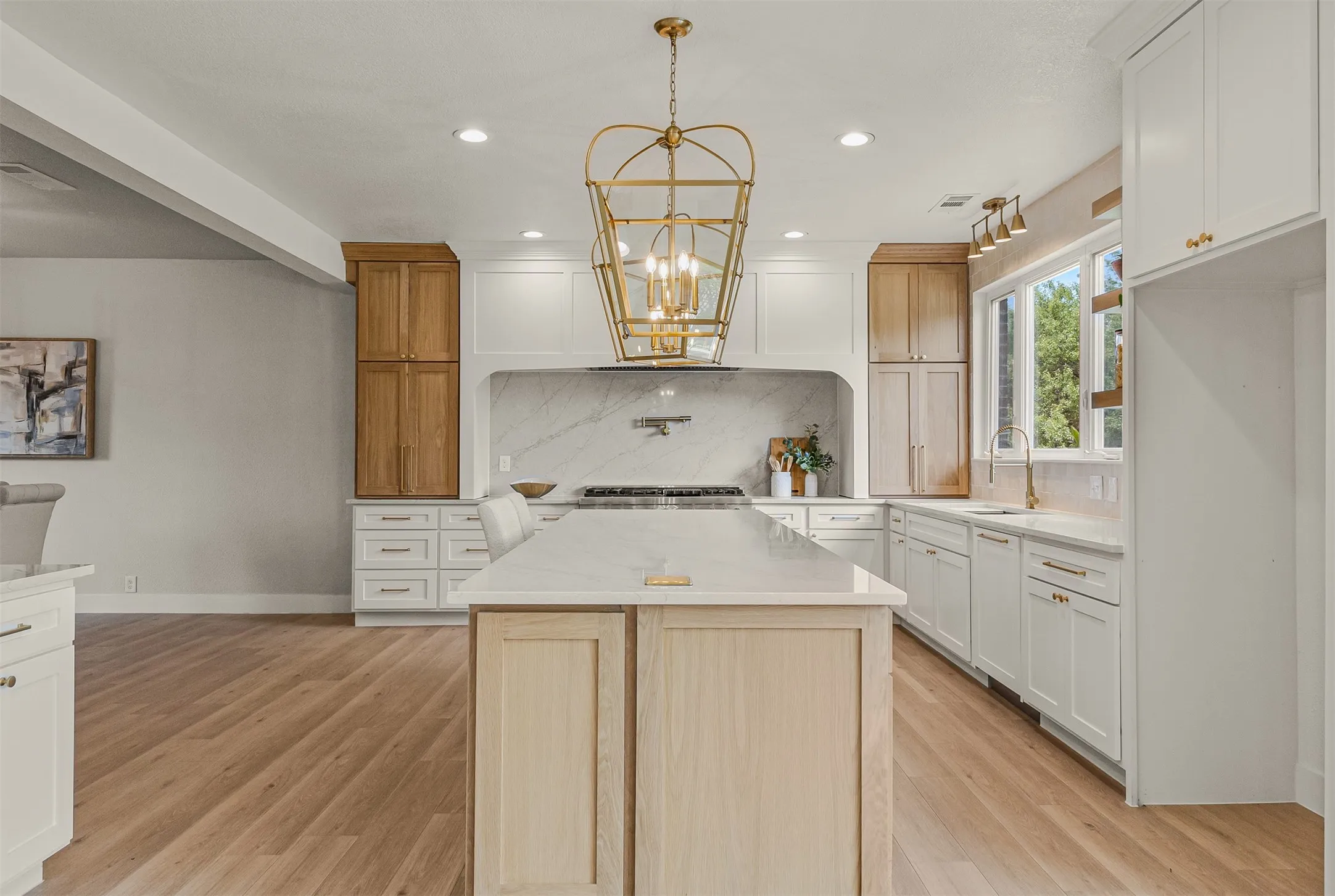 Kitchen featuring a large central island with a light wood base, white countertop, and seating