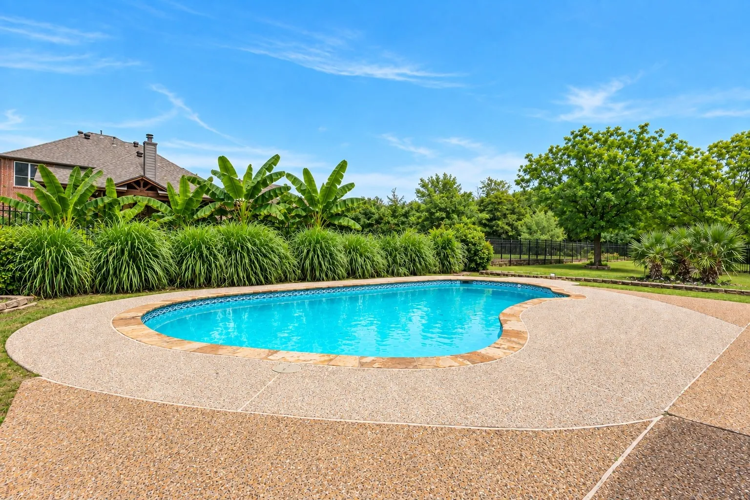 Freeform swimming pool with a surrounding exposed aggregate concrete deck