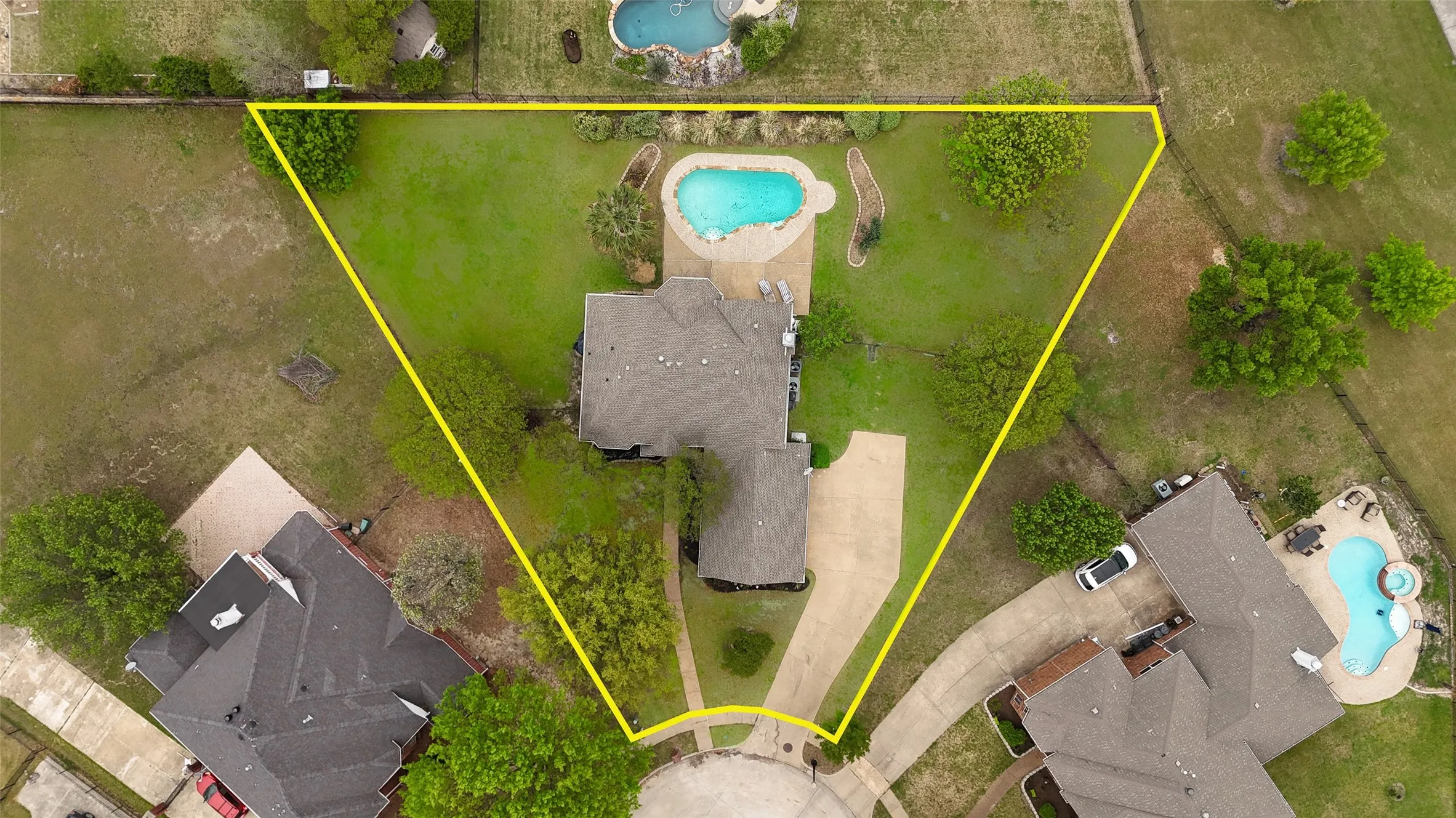 Aerial representation of the property, featuring a private swimming pool with integrated spa, an expansive green lawn, and mature trees