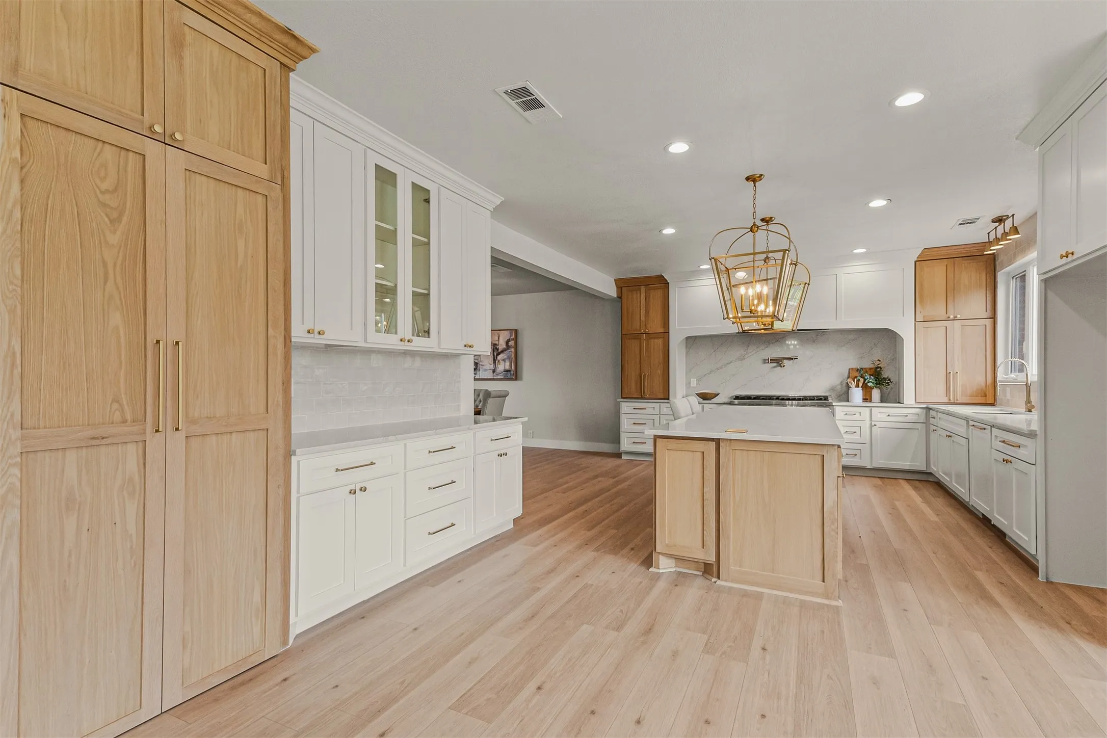 Light wood-finish flooring throughout, featuring a central kitchen island with a light countertop